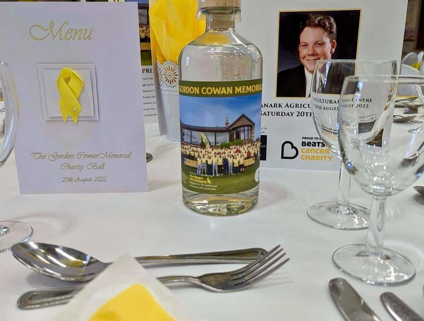 A charity ball table with the menu and a Gordon Cowan Memorial bottle