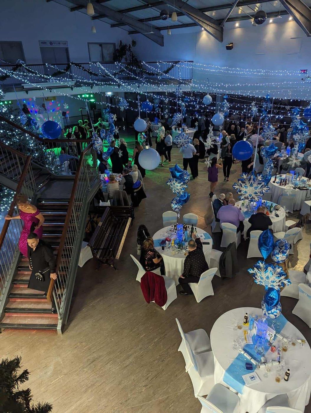 The charity ball venue dressed in blue and white with lights and table centrepieces