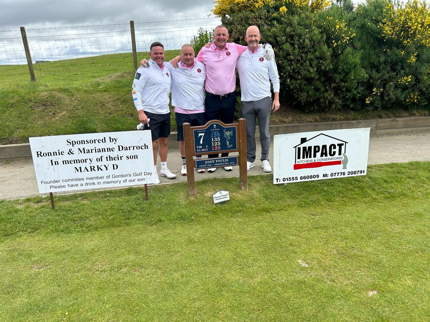 Golfers beside sponsor boards on the course