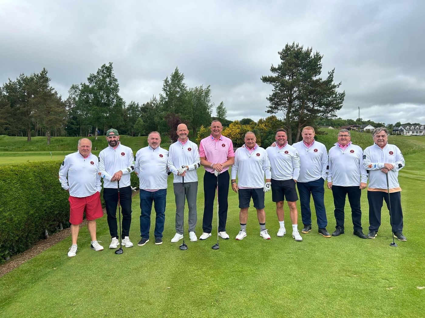 Golfers in white shirts lined up on the green