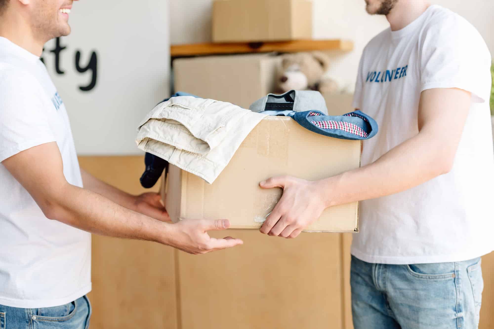 cropped-view-of-volunteers-holding-cardboard-box-with-clothes-in-charity-center.jpg